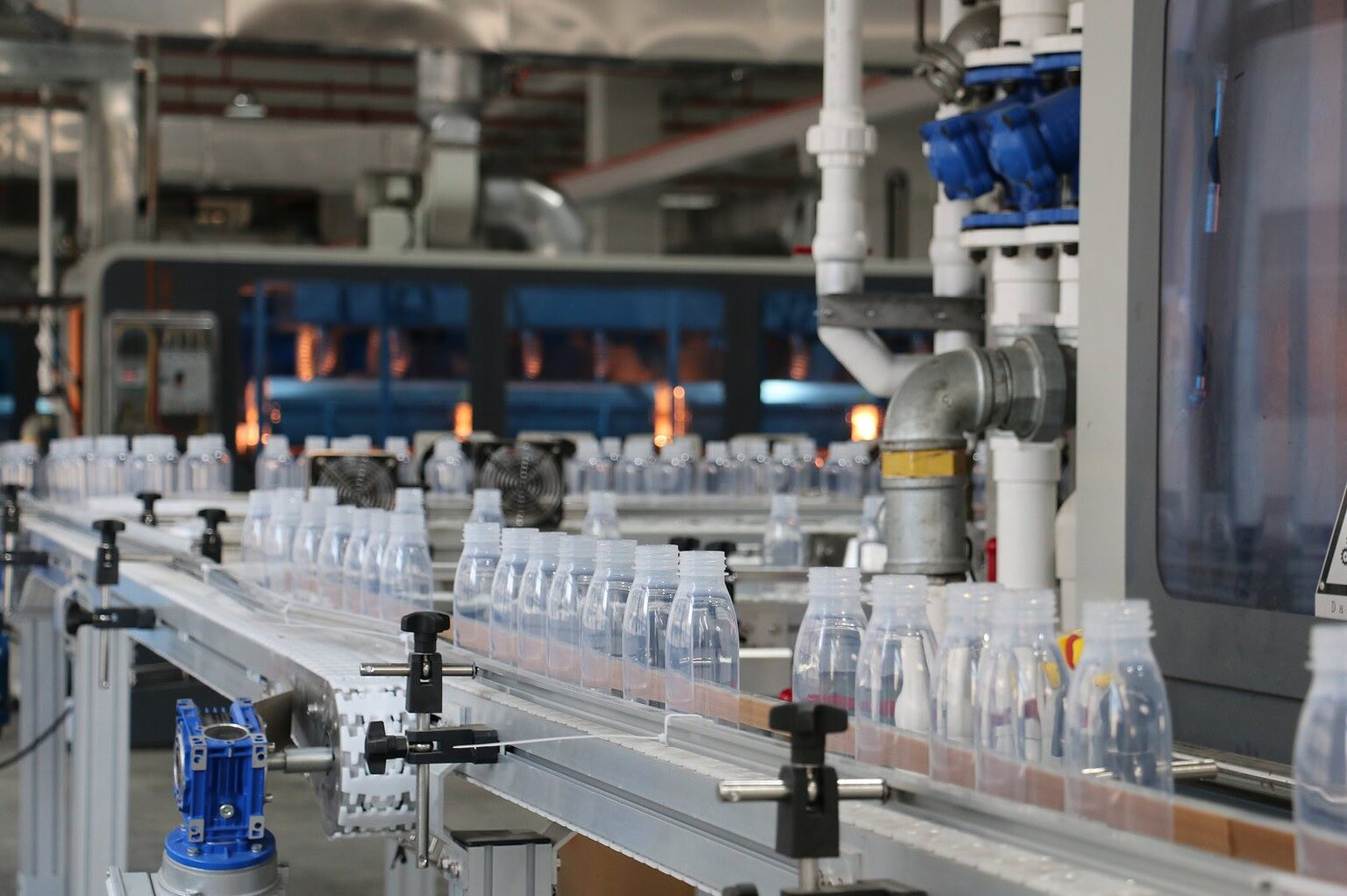 Automated production line for glass and plastic bottles in a manufacturing facility.
