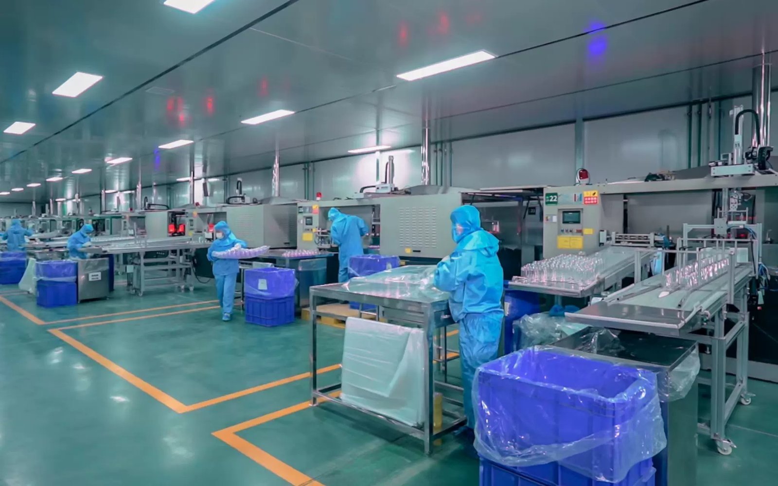 Modern glass and plastic bottle production line with workers in protective gear.