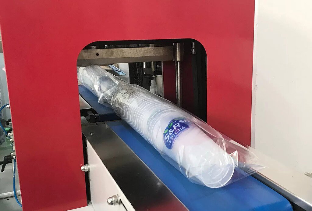 Industrial machine producing custom glass and plastic bottles on a production line.
